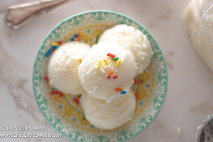 scoops of plain vanilla ice cream in a shallow colorful dish on a white marble surface 