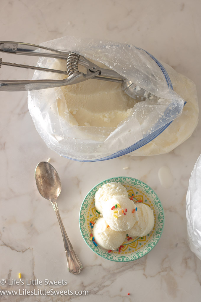 scoops of plain vanilla ice cream in a shallow colorful dish on a white marble surface with one silver spoon