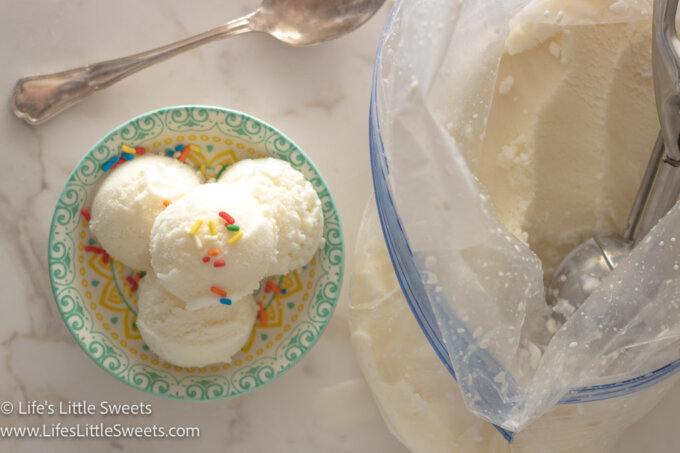 scoops of plain vanilla ice cream in a shallow colorful dish on a white marble surface with a silver spoon near a ziplock-style bag