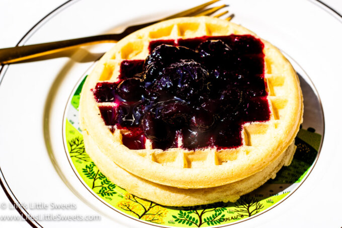 a horizontal view of waffles served with homemade blueberry syrup on top