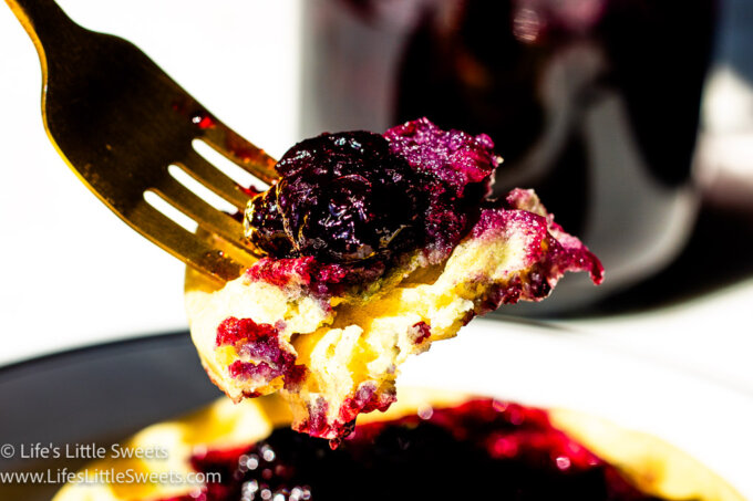 a gold fork with waffles and blueberry syrup