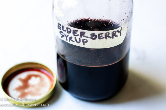 Homemade Elderberry syrup on a white marble background
