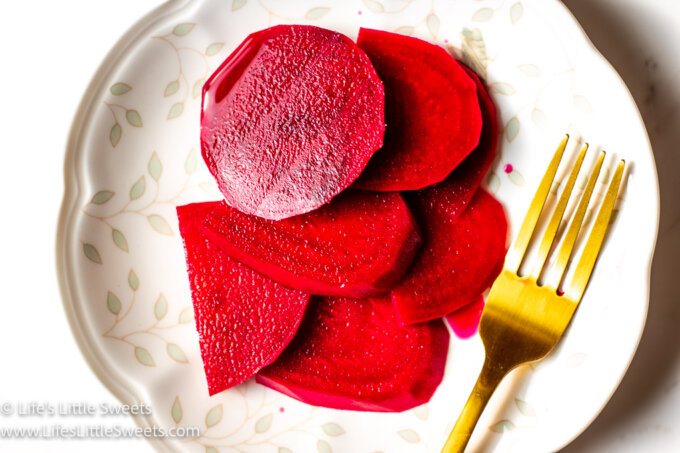 a plate of sliced pickled beets with a gold fork