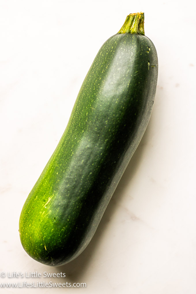 a green zucchini on a marble surface