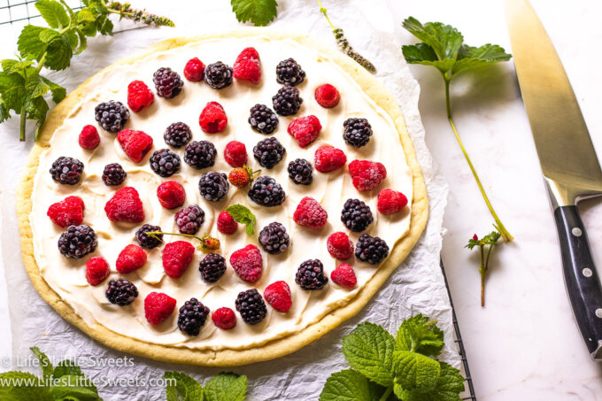 fruit pizza with fresh berries on top on parchment paper