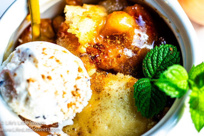 Peach slump in a white bowl with ice cream and mint