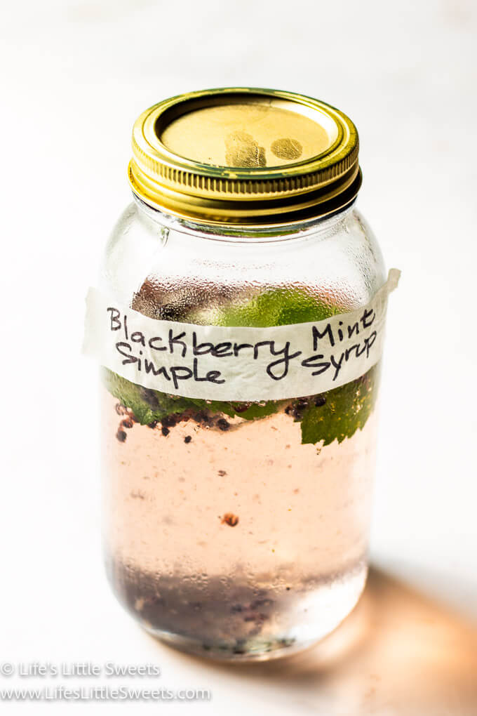 blackberry mint simple syrup in a lidded mason jar on a white background
