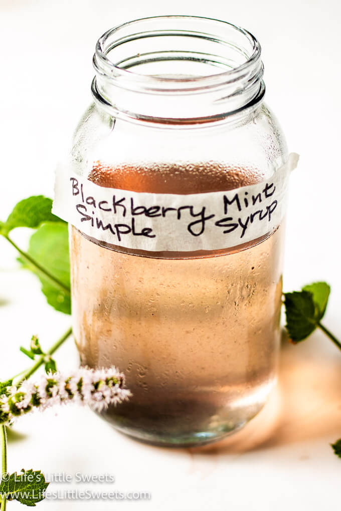 blackberry mint simple syrup in a mason jar with flowering mint