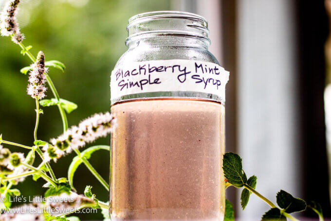 a purple-ish simple syrup in a clear mason jar with mint by a window