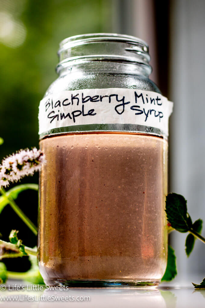 a simple syrup in a mason jar with mint in the background