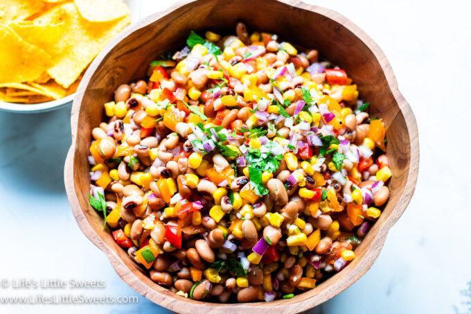 a pretty wooden bowl with Cowboy Caviar Recipe in it and yellow tortilla chips