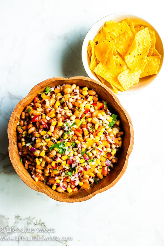 a wooden bowl with Cowboy Caviar with yellow tortilla chips