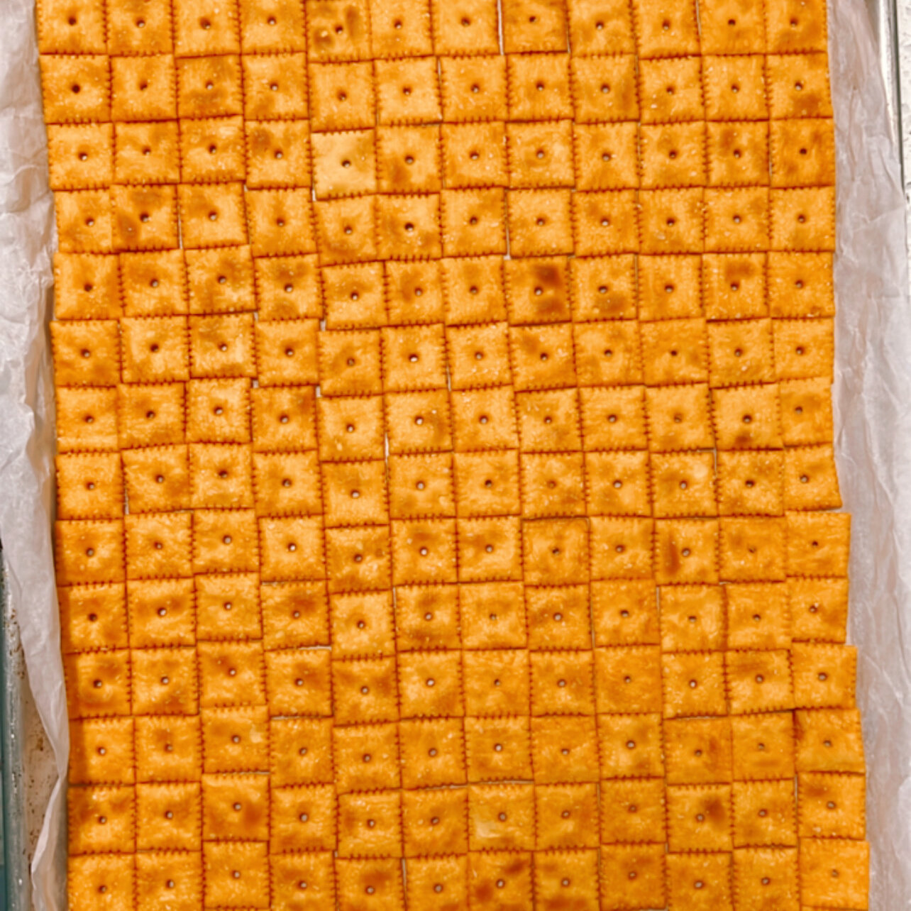 Regular Cheez-Its arranged on a parchment-lined rimmed baking sheet