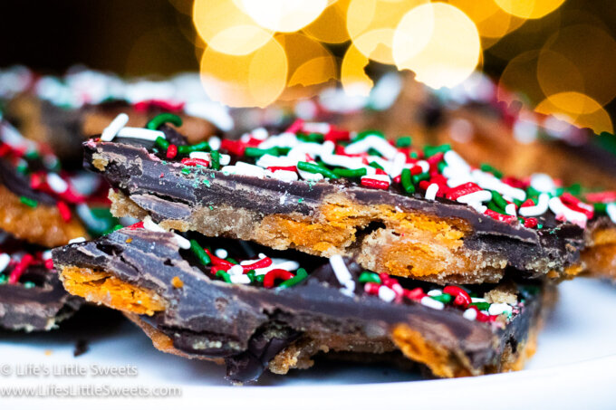 Cheez-It cracker Christmas toffee with Christmas sprinkles with white bokeh lights in the background
