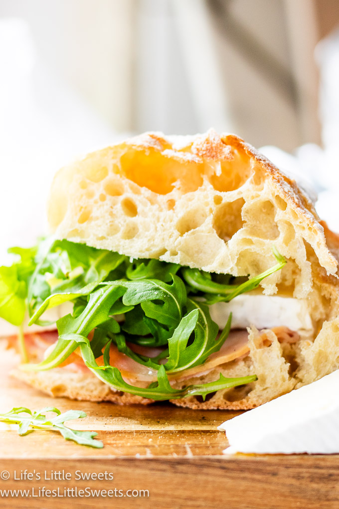 Ham Brie Arugula Sandwich in a light-filled kitchen on a wood cutting board