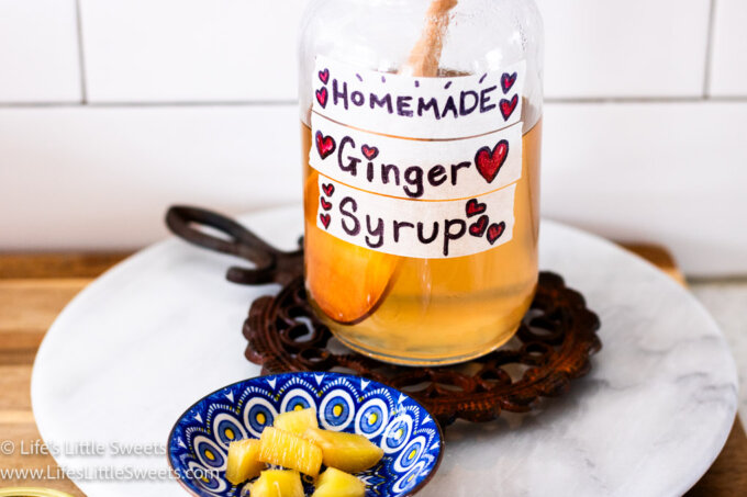homemade ginger syrup in a mason jar on a trivet with ginger candy in a blue small plate