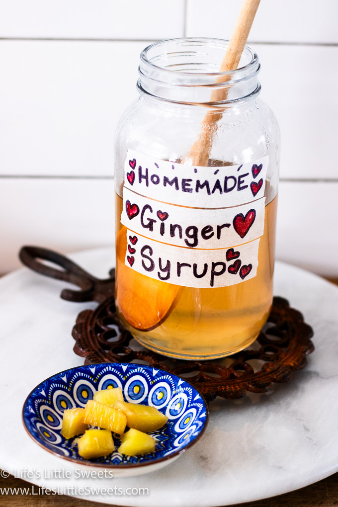 a glass jar filled with homemade ginger syrup and ginger candy on a marble lazy susan