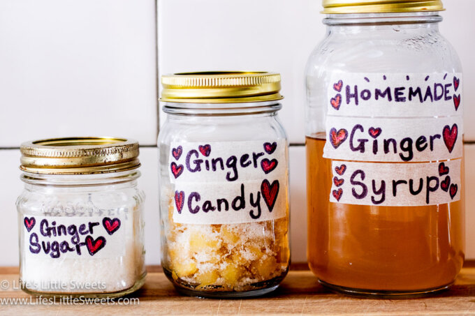 3 glass jars of Ginger sugar, Ginger candy and Ginger syrup on a wooden surface